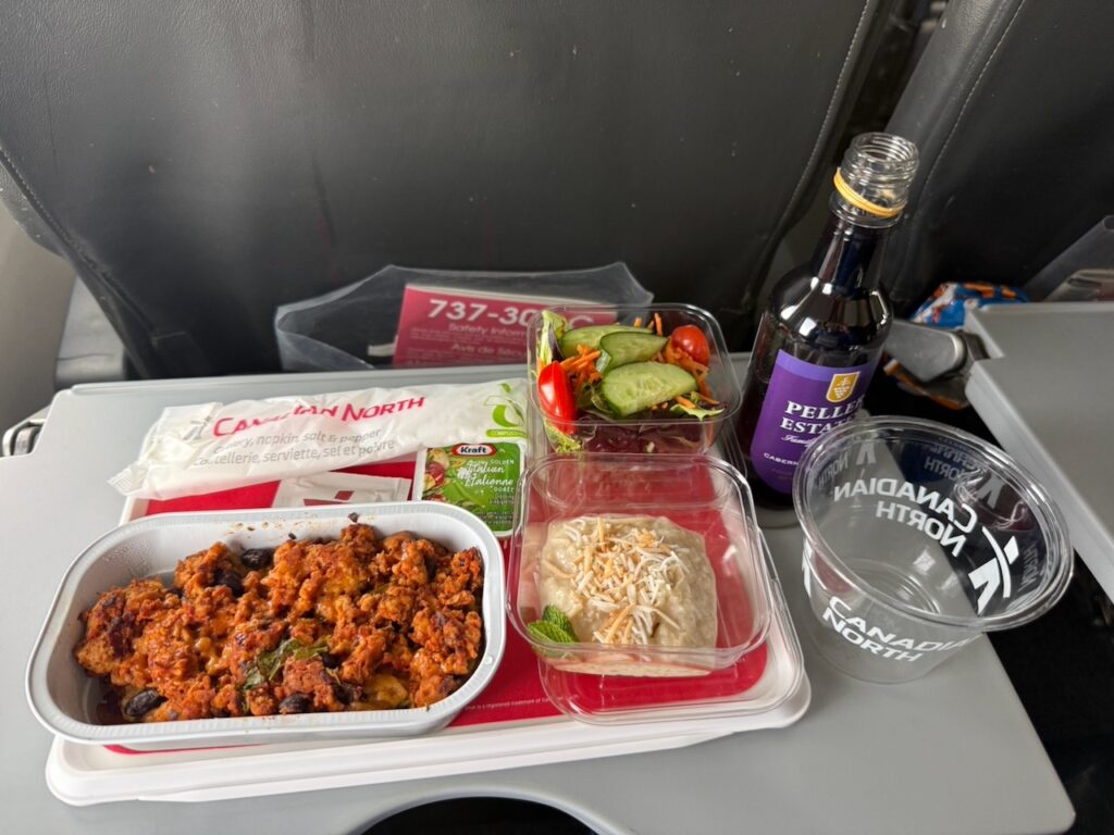 Chili chicken with pasta is served with a miniature bottle of red wine to the passenger.