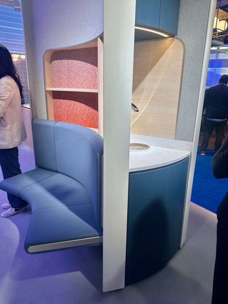 A plush bench as part of the E-Lounge concept sits alongside the water dispenser monument, as showcased on Boeing's stand at AIX 2026