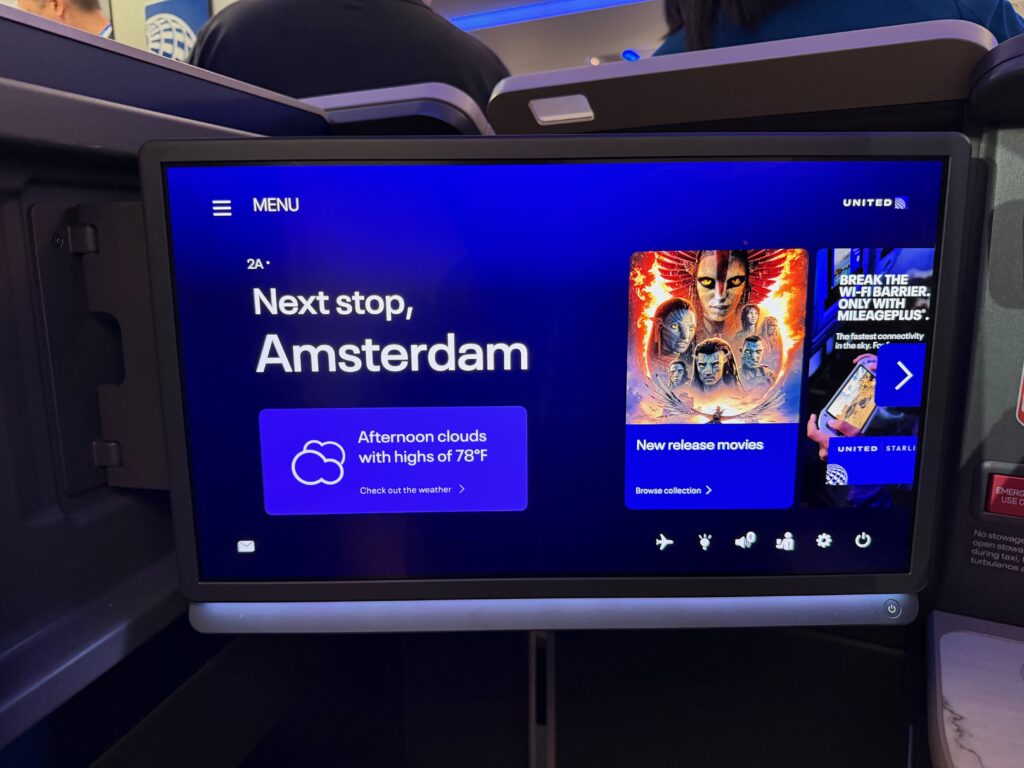 Large IFE screen in business class says, 'next stop, Amsterdam'