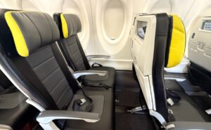 Seat duo on left side of A220. Seat are grey with yellow trim on the headrests.