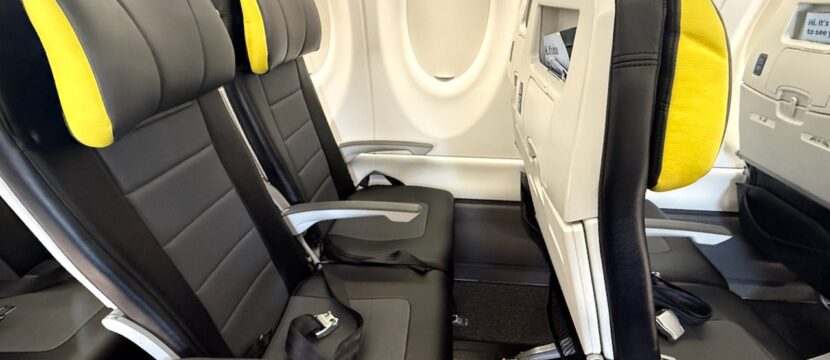 Seat duo on left side of A220. Seat are grey with yellow trim on the headrests.