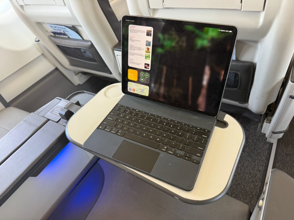 A laptop is sitting on the aircraft tray table.
