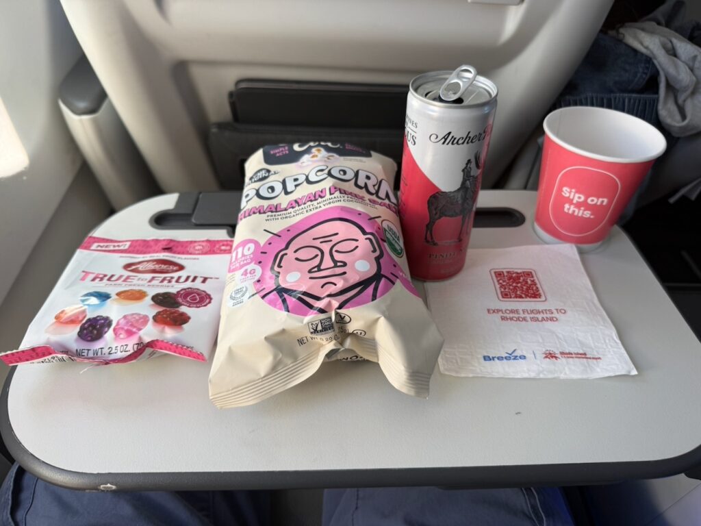 A snack and drink are on the aircraft tray table.