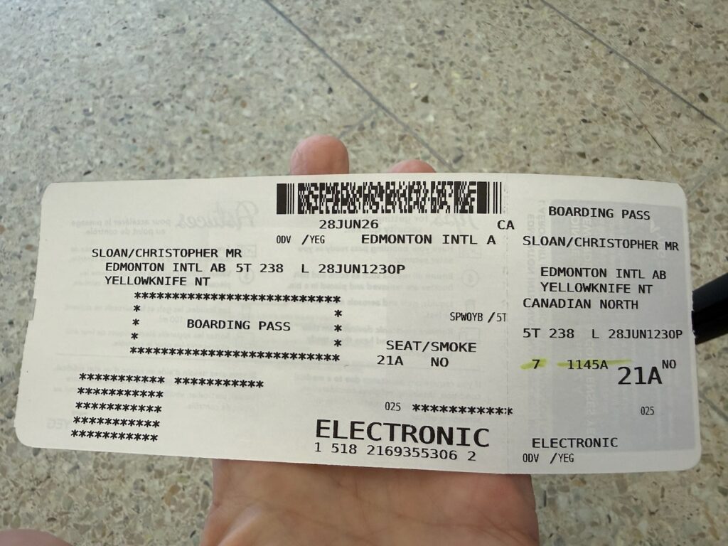 The passenger is holding a paper boarding pass for Canadian North.