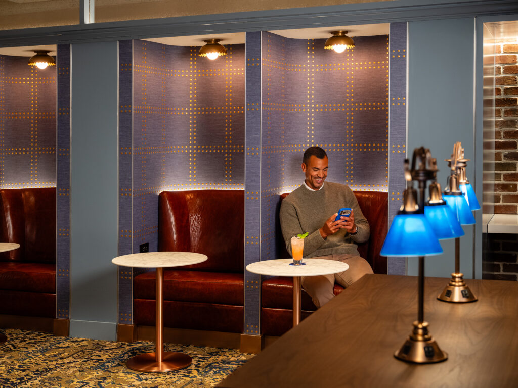 A man uses his device in a plush seat at BlueHouse in Boston