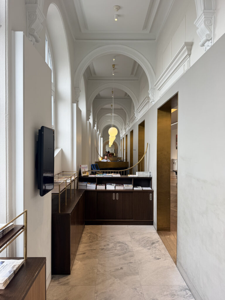 A neoclassical interior with high ceilings and narrow pillars along a thin corridor in the Eurostar Premier Lounge at Gare due Nord.