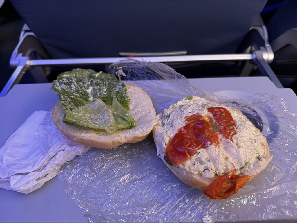 Curry chicken croissant sandwich is opened up and displayed on the tray table