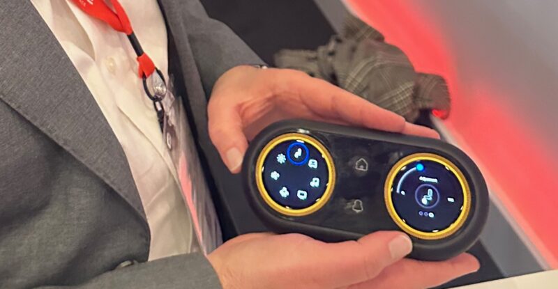 RAVE Aerospace's Ben Asmar holds up the new IFE and seat controller concept, which offers more accessible jog wheels as opposed to a touchscreen