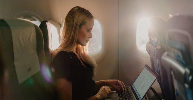 SAS passenger working on their laptop in flight, while using Starlink inflight Wi-Fi.