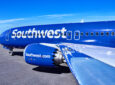 Southwest Airlines 737 MAX 8 with its bright blue and white livery is parked in the sunshine.