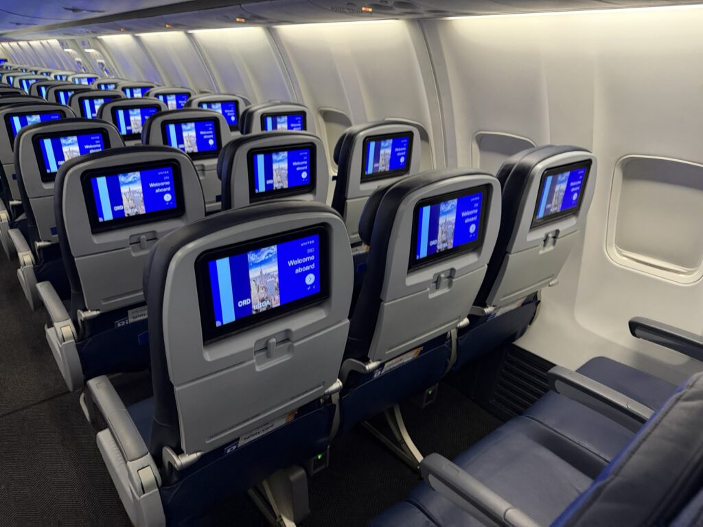 Rows of economy class seats with seatback screens on the United 737