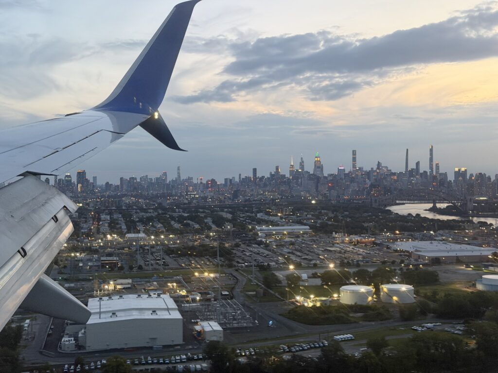 Looking out a United 737 cabin window at the wingtip and over the city below.