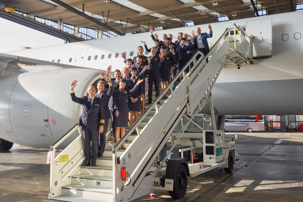 Lufthansa crew members wave from the jet stairs.