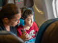 A mother and her son are looking out the window of the Hawaiian Airlines A330