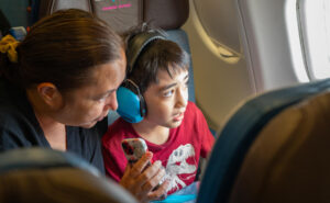 A mother and her son are looking out the window of the Hawaiian Airlines A330