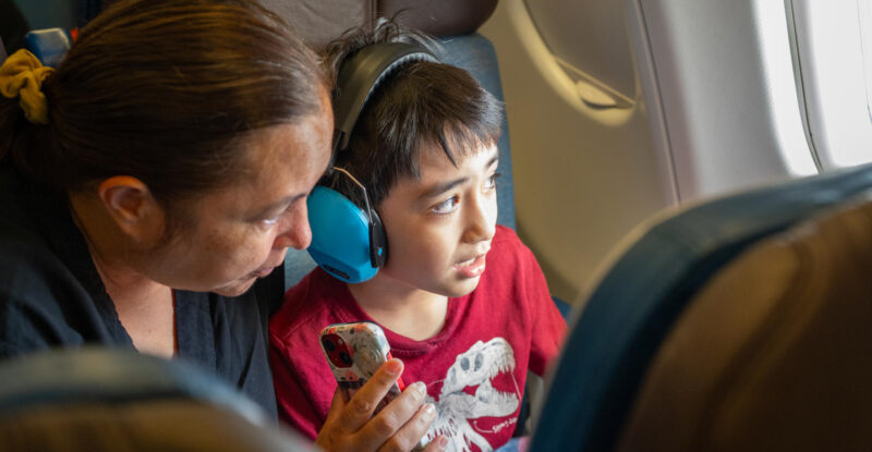 A mother and her son are looking out the window of the Hawaiian Airlines A330