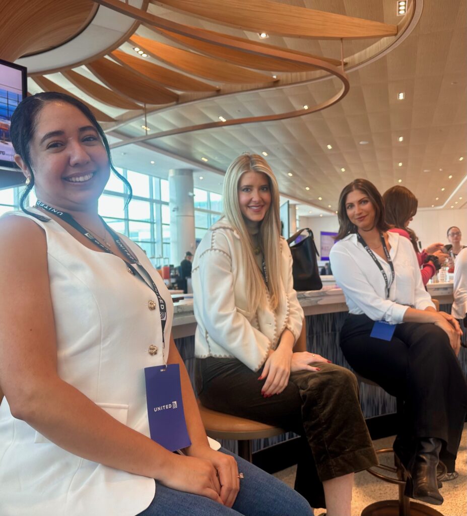 Three women are seated at a bar in the concourse