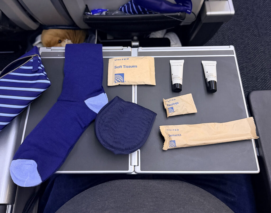 The contents of an amenity kit are laid out on the tray table aboard in Premium Plus aboard the United 787.