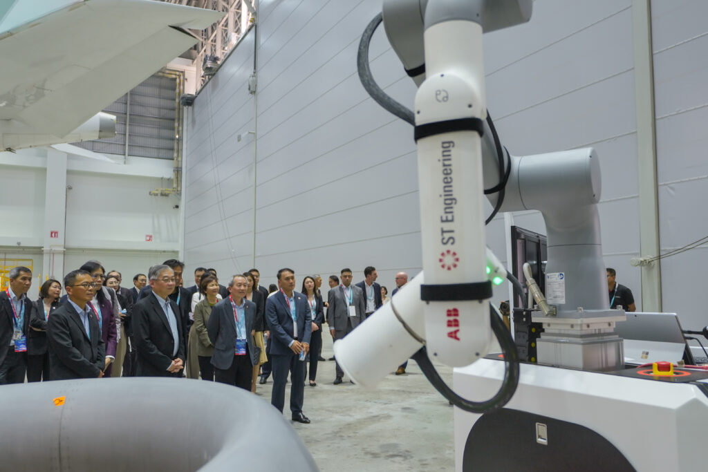 A crowd looks at a robot in the new ST Engineering facility. (Front row, second from left) Singapore Deputy Prime Minister and Minister for Energy, Trade and Industry (Trade) Gan Kim Yong with senior management from ST Engineering and its partners including the Singapore Economic Development Board looking at ST Engineering’s AI-VET (visual evaluation technology) solution at its newest airframe maintenance facility in Changi Creek, Singapore.