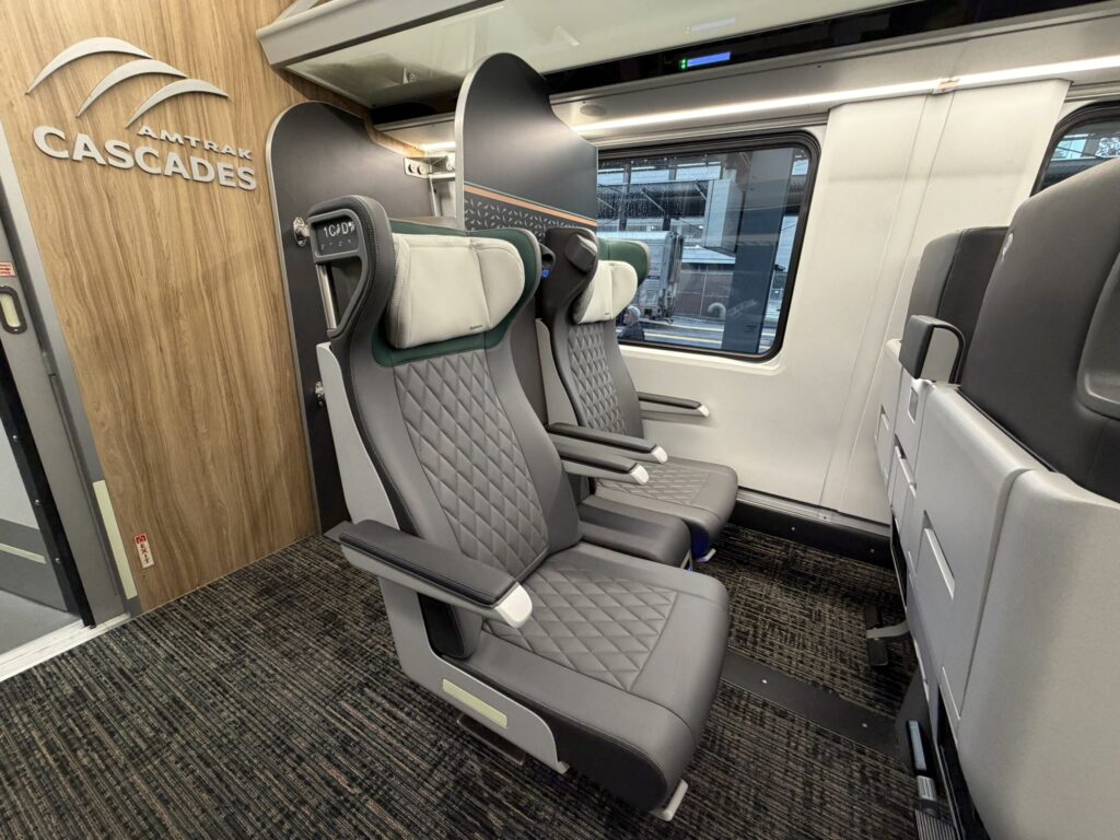 Business Class seats on the train with the words Amtrak Cascades seen on a divider partition
