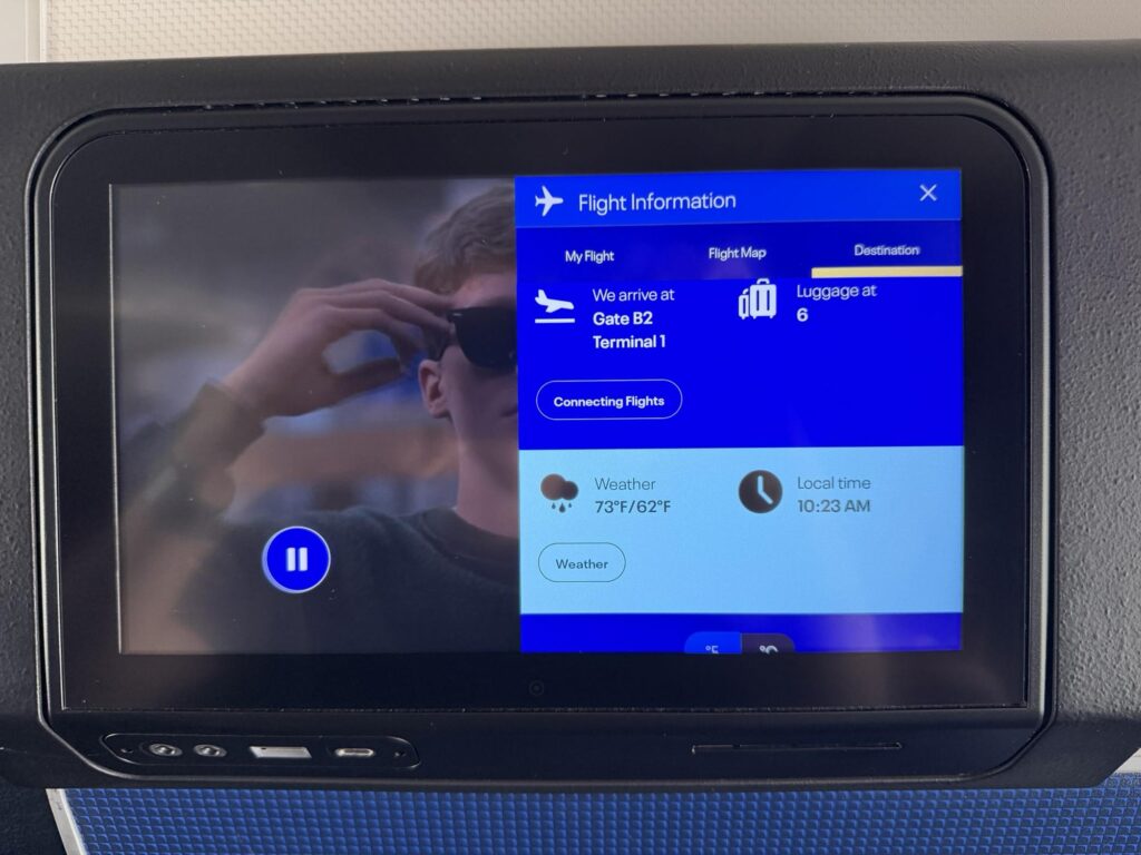 United Airlines IFE screen is showing flight information overlaid.